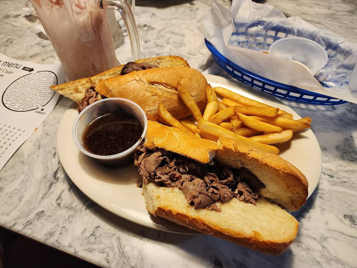 A roast beef sandwich with au jus sauce for dipping, served with a side of fries. (Au Jus Gravy)