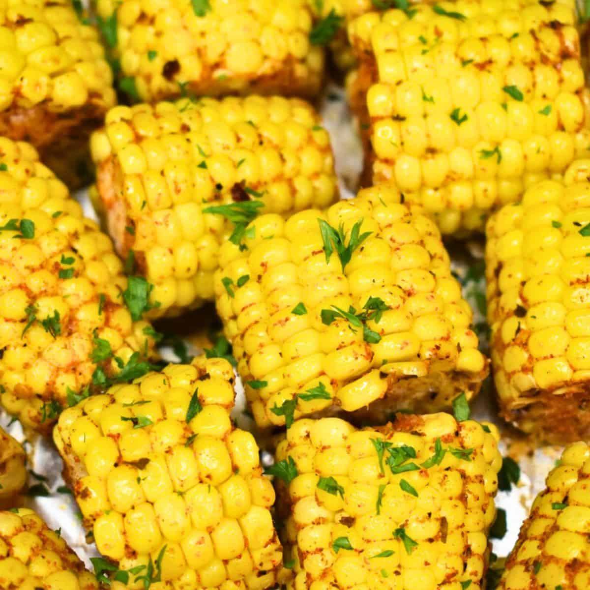 Roasted corn cob chunks with golden plump kernels, seasoned and garnished with fresh parsley, brightly lit, no