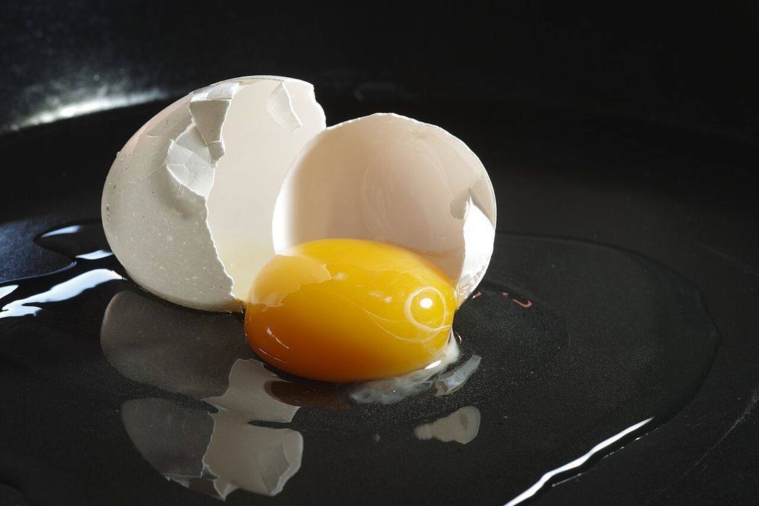 Broken egg on black surface (Egg Yolks)