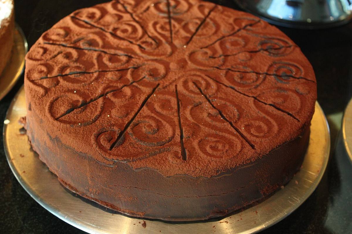 Piece of chocolate cake on a white plate decorated with chocolate sauce (German Chocolate Cake)