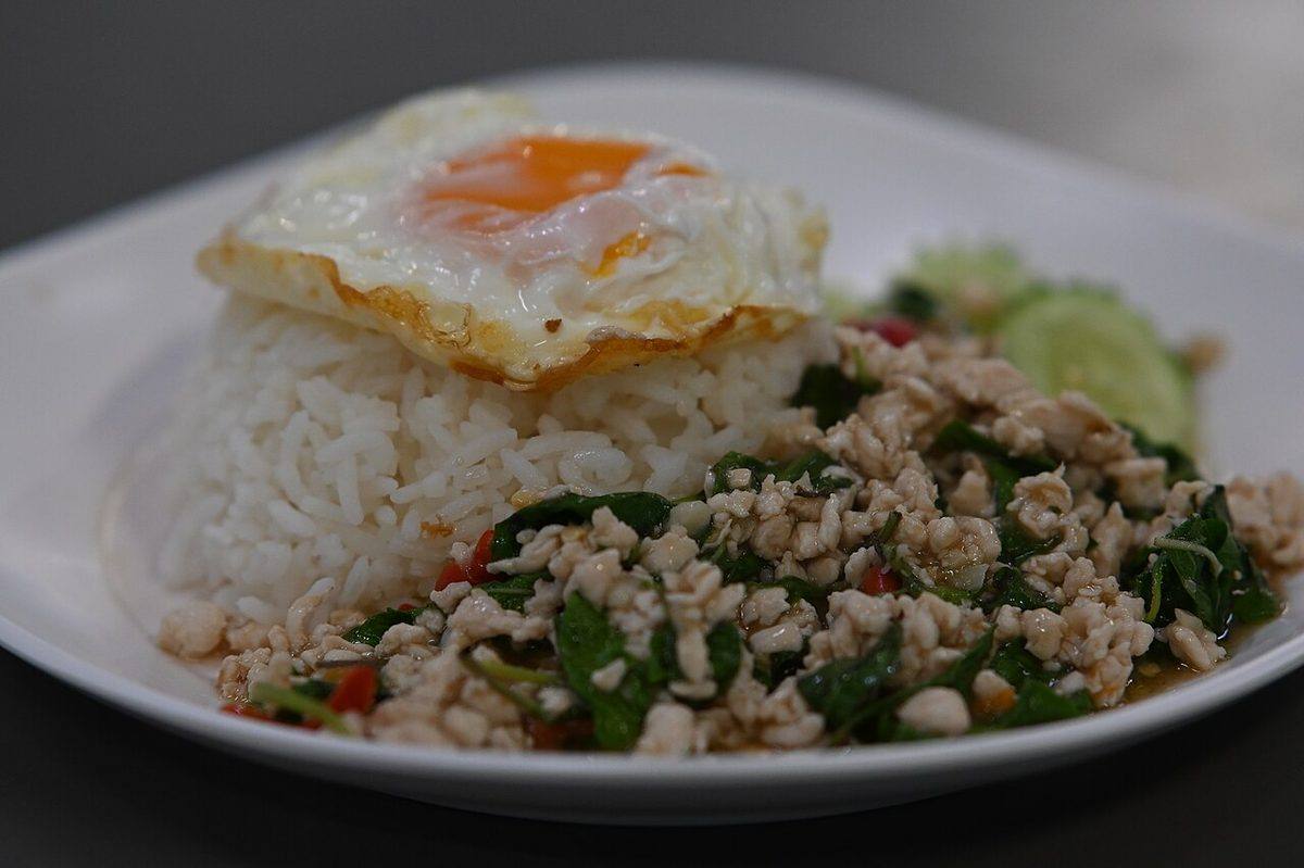 DFC 0804 A plate of steamed white rice topped with a runny fried egg served alongside stir-fried minced...