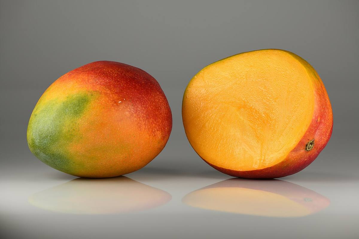 Whole ripe mango and a cut half