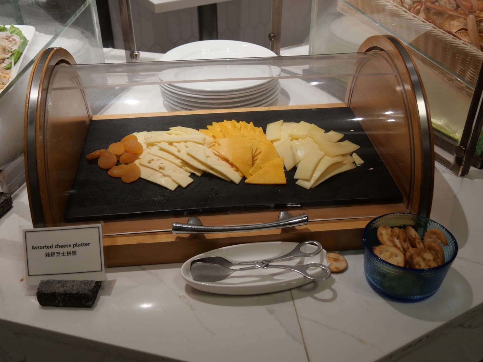 A cheese board with three kinds of cheese, sliced and ready to serve