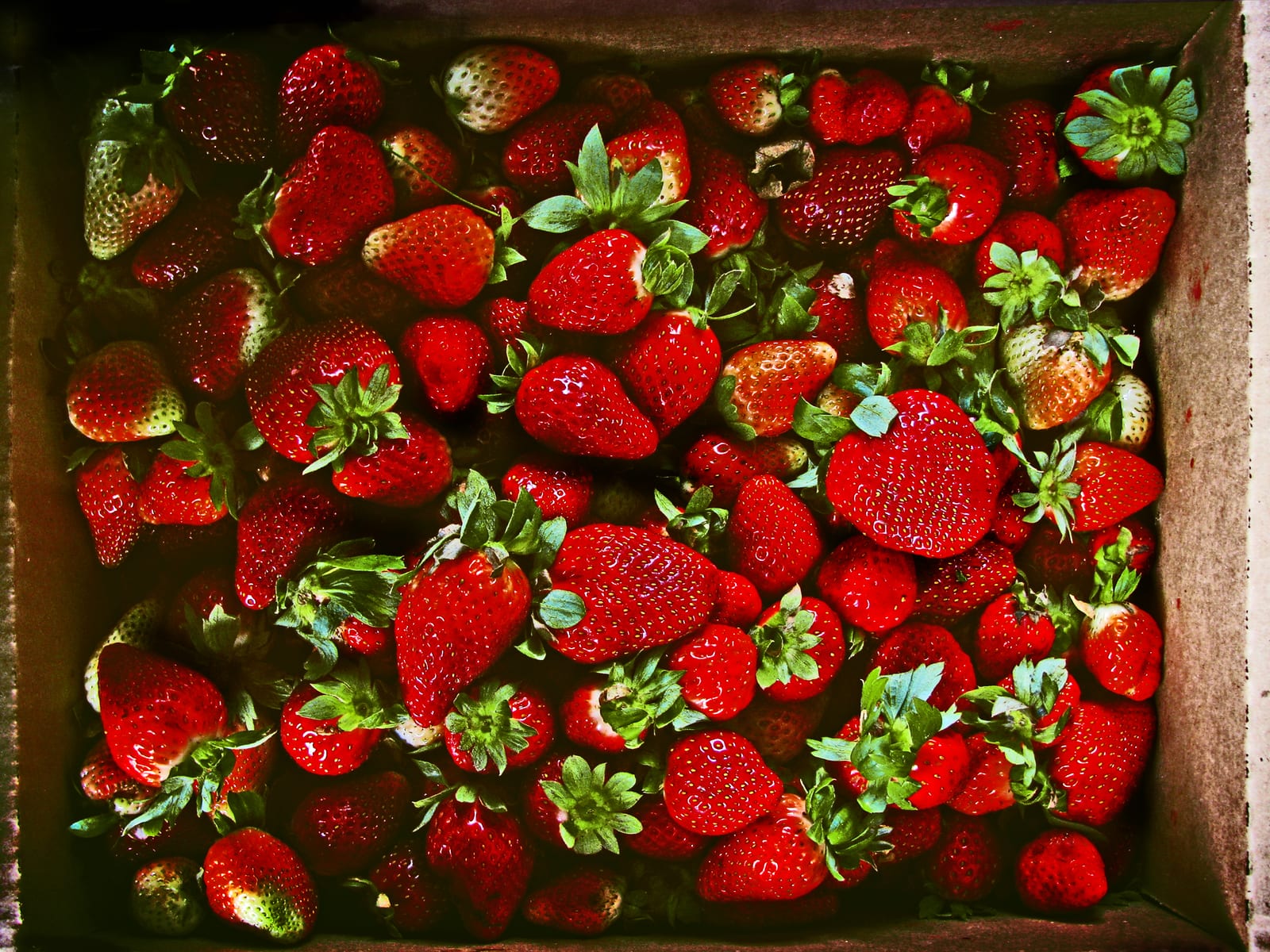 A wooden crate filled with ripe red strawberries