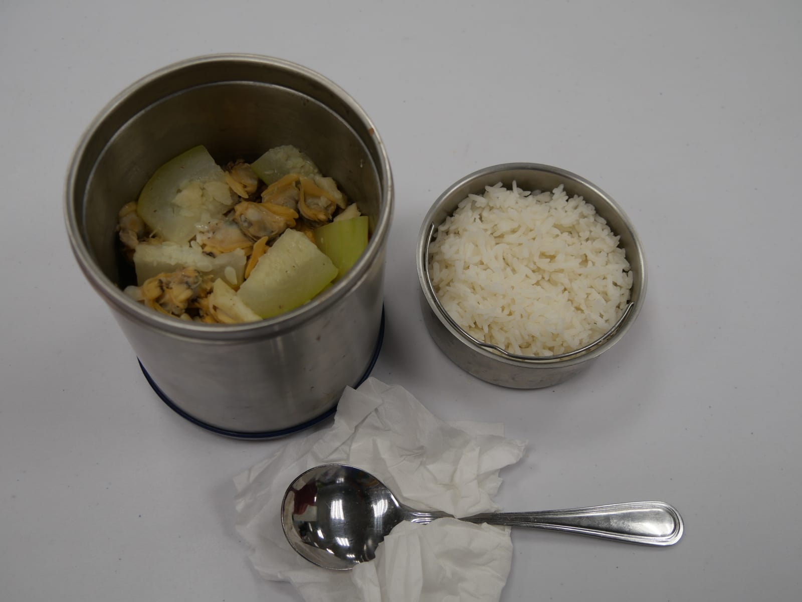A cooked dinner packed into stainless steel lunch containers